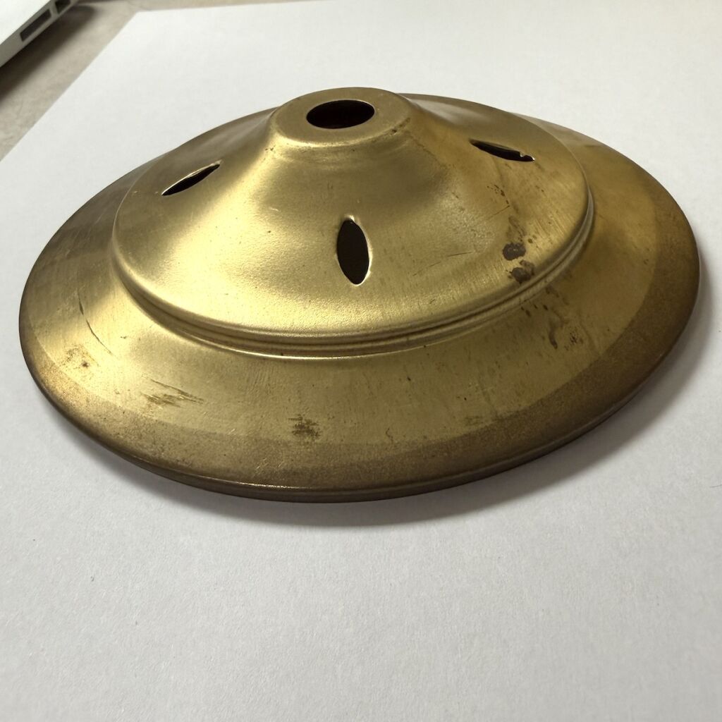 Brass domed vent cover with a central hole and four oval vents on a white surface.