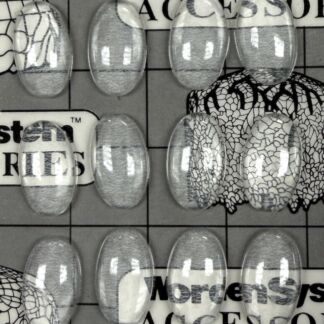 Close-up of oval glass cabochons arranged on a printed grid background with a visible label reading 'Jewels Made in Germany' and partial brand text in the background