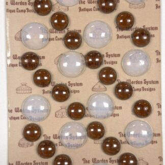 Brown and clear glass lamp knobs arranged on a beige display card labeled The Worden System Antique Lamp Designs.